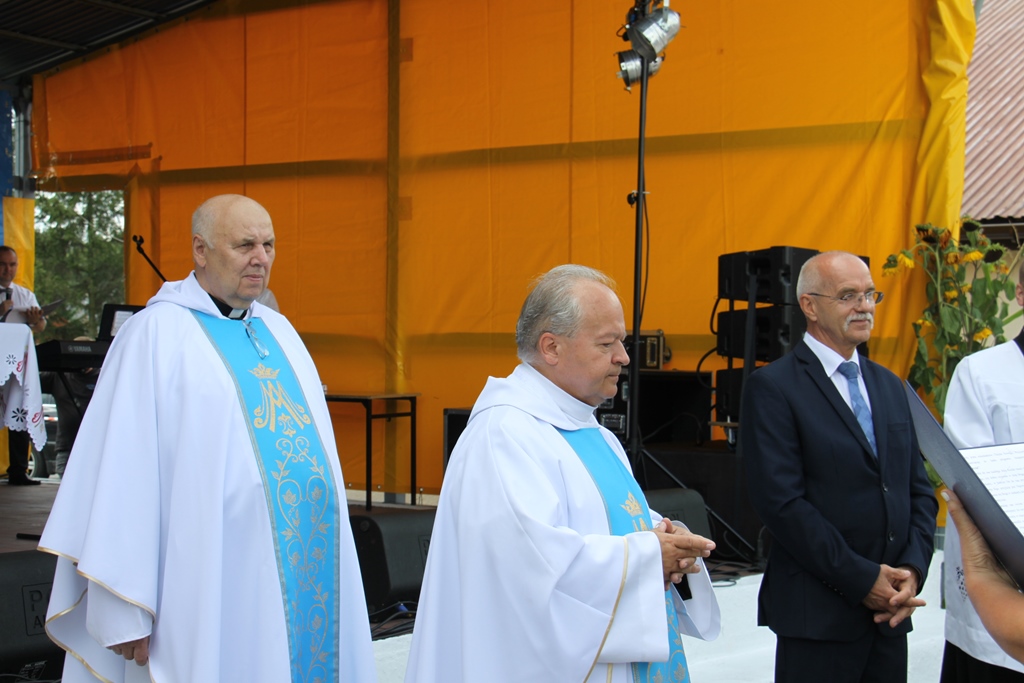 Dwaj księżą przed ołtarzem oraz bursmitrz w oczekiwaniu na prezentację kolejnego wieńca